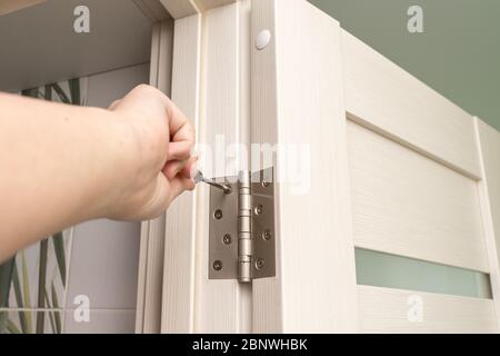 door frame installation. the master installs the door and screw the hinge with a screwdriver Stock Photo