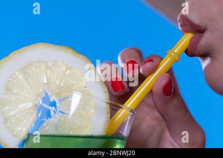 On the close-up you can see a straw in the mouth, which is drunk by a woman. Stock Photo