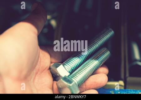 hand holds an iron bolt. repair concept. close-up. Stock Photo