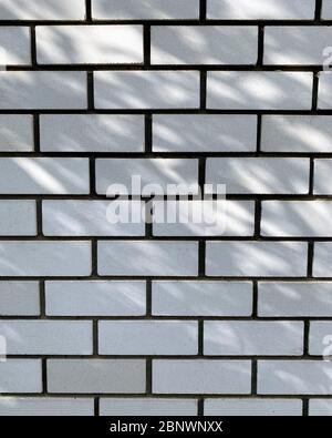 Brickwall texture background or backdrop with stains and cement smears. the rays of the sun fall on the wall. Stock Photo