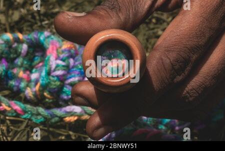 A Person holding a Pot Smoking Pipe, also known as Chillum, the relection of the colorful Pipe Holder (placed on the back) can be seen on the inside t Stock Photo