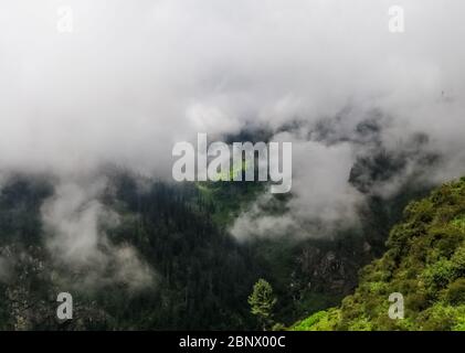 Landscape of sunlight falling through the clouds on a distant mountain grassland while the clouds are covering it across. The foreground is shining br Stock Photo