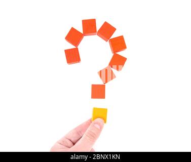 Female hand builds a question mark out of wooden blocks. Top view, isolated on white. Comprehension concept. Stock Photo