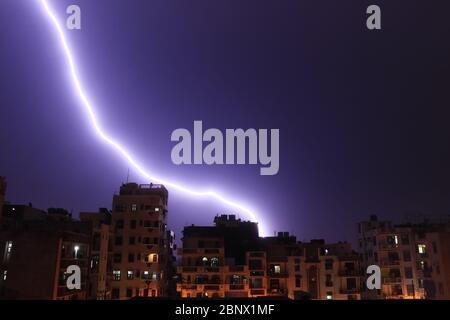 Lightning Strike from above falling down in a city, behind bulidings, stunning glow nightscape, 5K Stock Photo