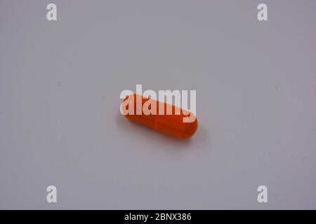 Medical preparations, medical pills in an orange capsule are located on a black background. Stock Photo