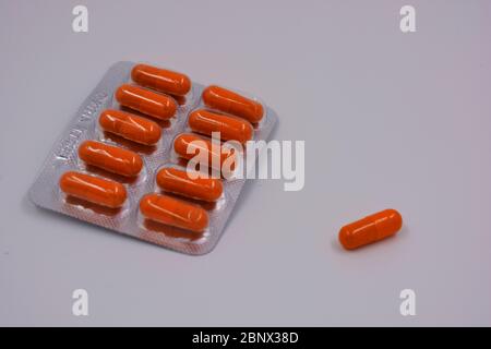 Medical preparations, medical pills in an orange capsule are located on a black background. Stock Photo