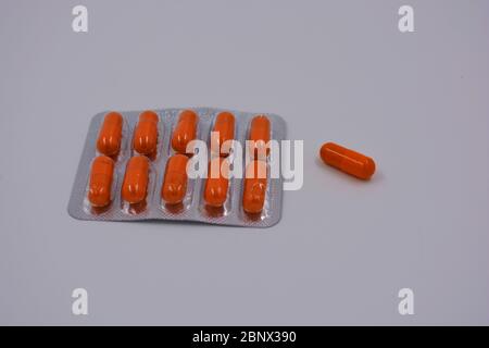 Medical preparations, medical pills in an orange capsule are located on a black background. Stock Photo