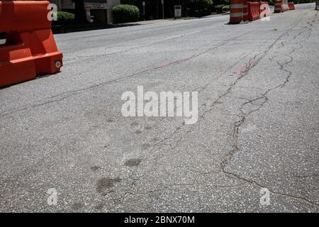 Cracked asphalt street with open space between traffic barrels and orange and white plastic barricades, creative copy space, horizontal aspect Stock Photo