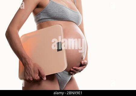 pregnant woman holding the scales on a white background Stock Photo
