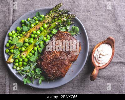 roasted beef steak, mutton with asparagus green peas on a plate, white sauce Stock Photo