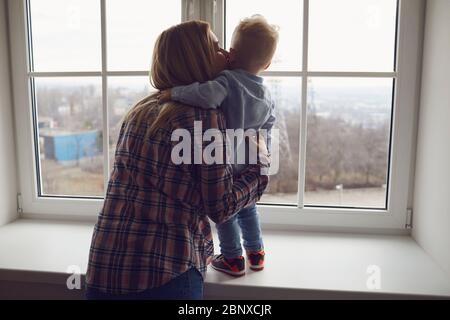 Children Protection Day. Mothers Day. Mother and baby are looking out the window. Stock Photo
