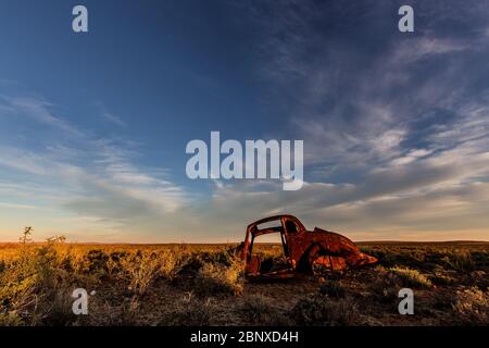 old car wreck under nice clouds in middle of nowhere Stock Photo