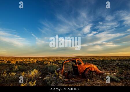 old car wreck under nice clouds in middle of nowhere Stock Photo