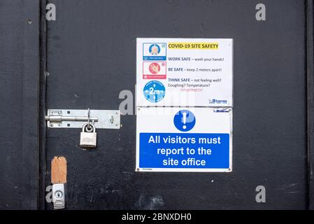 Construction COVID-19 site safety warning sign during Coronavirus pandemic lockdown period. Notice for visitors to a building site on access door Stock Photo