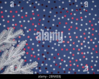 White fir-tree branches for Christmas. Colored snowflakes on a blue background. The view from the top. Stock Photo