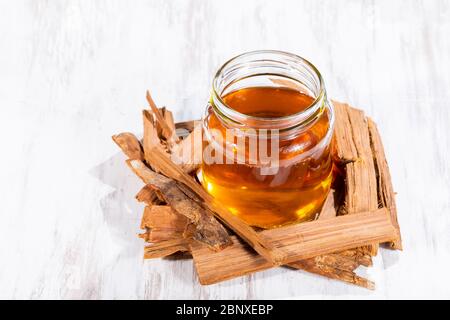 Tea and bark of cat's claw plant on wooden background, uncaria tomentosa Stock Photo