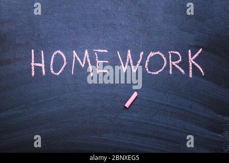 The word homework is written in chalk on a blackboard. Stock Photo