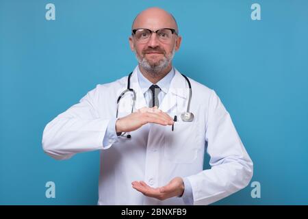 Handsome mature doctor holding something big between hands with copyspace Stock Photo