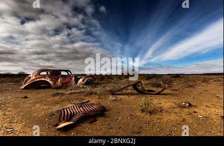 old car wreck under nice clouds in middle of nowhere Stock Photo