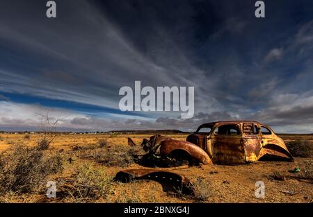 old car wreck under nice clouds in middle of nowhere Stock Photo