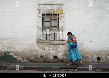Indigenous elderly Mayan woman walking on cracked sidewalk, wearing traditional clothing. Quetzaltenango, Guatemala Stock Photo