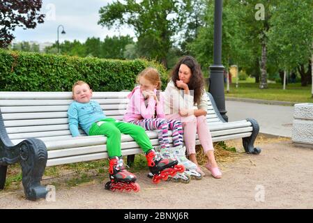 The boy with his mother and sister resting after skating on a be Stock Photo