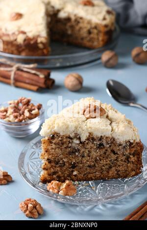 Homemade crumb cake with walnuts and cinnamon in plate on light blue background, ready to eat, closeup, Vertical format Stock Photo