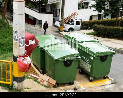 Medellin, Colombia, October 15 2019: containers for solid waste management recollection system in a hill in Medellin next to a pay phone and a woman w Stock Photo