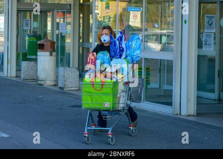 Tuscany, Italy 04/10/20: Easter shopping during coronavirus pandemic: an italian white lady wearing COVID-19 protective mask pushes a cart full of Lin Stock Photo