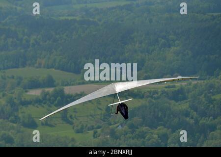 Kozakov, Czech Republic. 16th May, 2020. A Hang-glider steering an ultra light air craft has taken off from Kozakov (100 kilometers north from Prague) in the Czech Republic. Hang gliding is an air sport or recreational activity in which a pilot flies a light, non-motorised foot-launched heavier-than-air aircraft called a hang glider. Typically the pilot is in a harness suspended from the airframe, and controls the aircraft by shifting body weight in opposition to a control frame. Credit: Slavek Ruta/ZUMA Wire/Alamy Live News Stock Photo