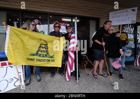 Vancouver, USA. 16th May, 2020. Kelly Carroll who officially opened her business, The Pet Biz, in Vancouver, Wash., on May 16, 2020, holds an American flag as she stands next to her sisters Neetz Martin and Diana Carroll. The opening is a direct violation of Governor Jay Inslee's orders for non-essential business to remain closed at this time, but Kelly, who has already been operational for five days, insists she need to open to support her grand-daughters. (Photo by Alex Milan Tracy/Sipa USA) Credit: Sipa USA/Alamy Live News Stock Photo