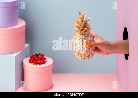 Hand showing a golden pineapple on blue background Stock Photo