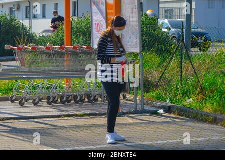 An italian white woman with coronavirus protective mask and sanitary gloves busy texting on her smartphone. Europe fearing second wave of covid-19 Stock Photo