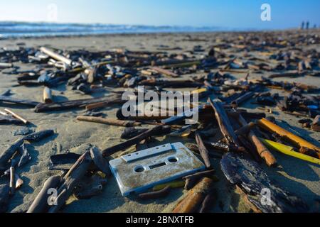 Scene of pollution from a beach: an old plastic tape cassette has washed up on the dirty shore. Plastic in the ocean. Symbol of enviromental disaster. Stock Photo