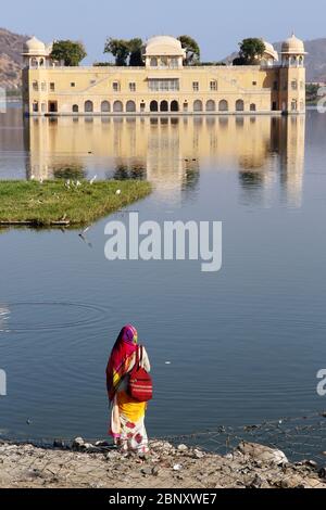 Rajasthani woman in beautiful sari observing the famous palace on the lake in Jaipur Stock Photo