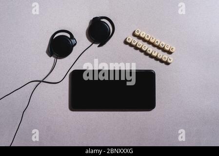 Close up flat lay of mobile phone with headphones and little wooden bricks with black letters. Distance learning online education concept. Stock Photo