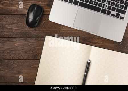 Office stuff with notepad, laptop and mouse on wooden desk. Flat lay shot, working at home concept Stock Photo