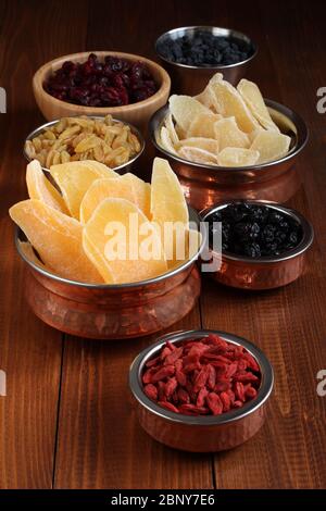 Slices of candied ginger root, pieces of dried mango fruits, dried blueberries and goji berries, dried cranberries, golden and blue raisins in small b Stock Photo