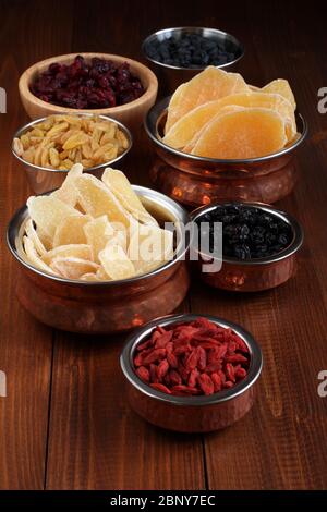 Slices of candied ginger root, pieces of dried mango fruits, dried blueberries and goji berries, dried cranberries, golden and blue raisins in small b Stock Photo