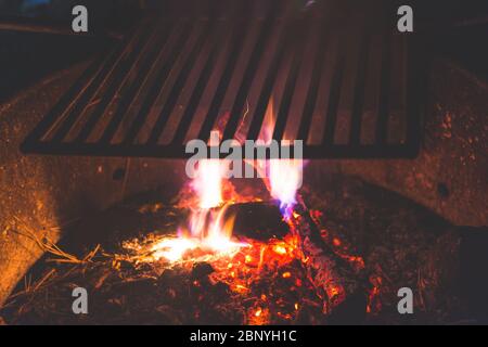Stainless Steel BBQ Grill over bonfire im camp site in campground at night. Stock Photo
