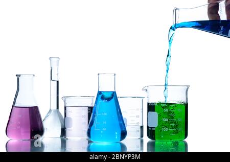 Scientist put blue liquid into measuring beaker  with laboratory glassware and liquids of different colors, Flasks and measuring beaker isolated on wh Stock Photo