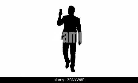 Silhouette Young businessman using smartphone to videocall to business partner while walking. Stock Photo