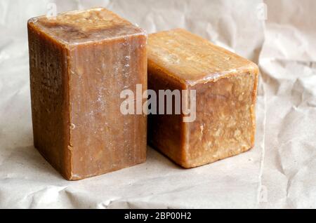 Two pieces of laundry soap on a plain background. Rectangular pieces of new soap. Natural hygiene products. Place for text. Selective focus. Stock Photo