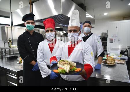 Mixed race team Portrait of group chefs standing together in the kitchen at restaurant wearing protective medical mask and gloves in coronavirus new n Stock Photo