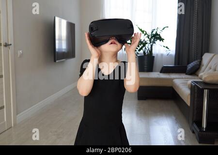Teenage girl wearing virtual reality goggles headset and playing, vr box. technology, new generation, progress concept. Girl trying to touch objects Stock Photo