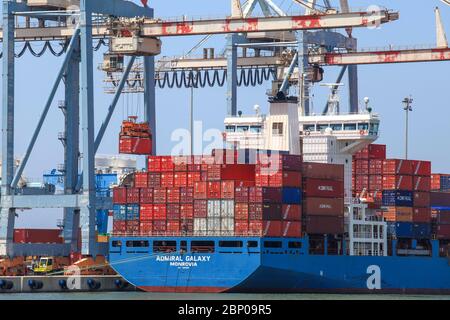 Large Container Ship docked at a commercial port during loading and unloading operation Stock Photo