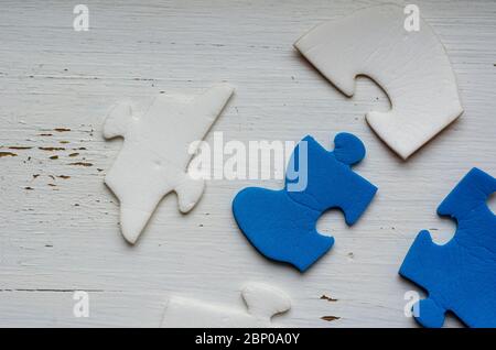 Unassembled puzzle pieces on white cracked paint. Blue and white puzzle pieces on an old wooden table. The concept of an old unsolved problem. Psychol Stock Photo