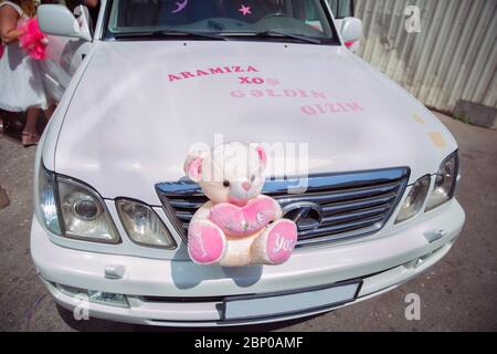 A bear doll placed in front of a car for circumcision . .Bear toys . Bear puppet sitting on top of the car. Stock Photo