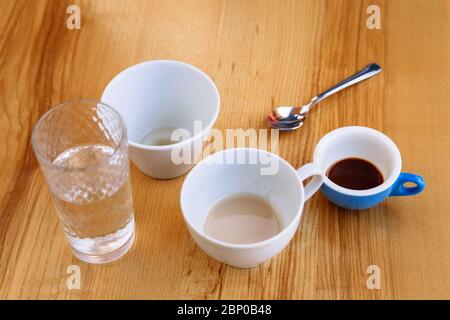 Dirty coffee cups, cappuccino and a glass of water stand on a wooden table. Coffee break. Stock Photo