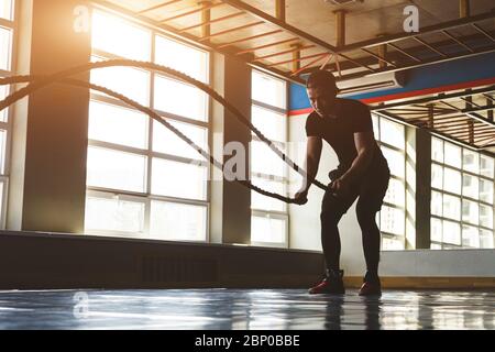 Exercise with ropes. The athlete is training in the gym opposite large panoramic windows. Stock Photo